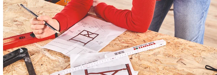 Person zeichnet auf Bauplan